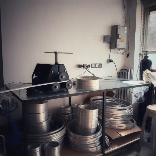 a table with a machine and rolls of metal